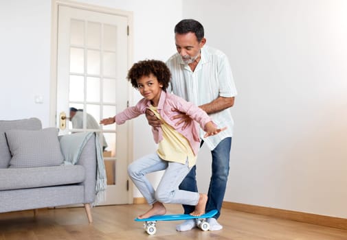 Senior Grandpa Teaching Grandson To Ride A Skateboard At Home