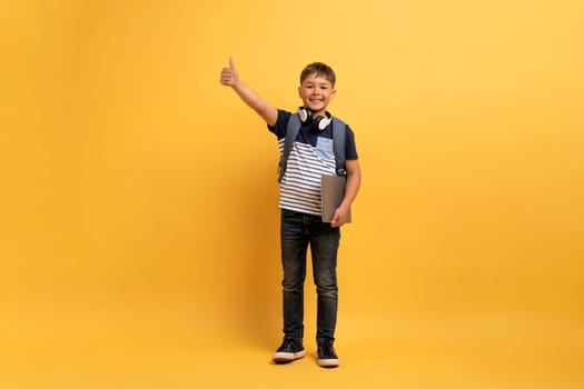 Cute schoolboy showing thumb up and smiling