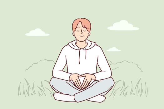 Man meditates sitting on grass and practices yoga to restore strength and put thoughts in order