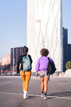 two women with sport clothes walking along a city