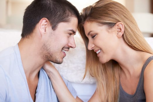 Face, intimacy and couple relax and bond in a living room happy, sweet and sharing romance in their home together. Smile, embrace and woman with man in a lounge for conversation, love and hangout.