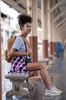 Young Asian African woman traveler with backpack in the railway train, traveler girl walking stand sit waiting take a