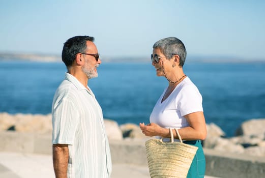 Mature Tourists Standing Looking At Each Other Near Sea Outdoors