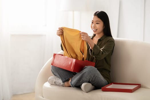 Happy young korean woman unpacking parcel at home