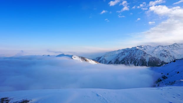Ocean of clouds in snowy mountains at dawn