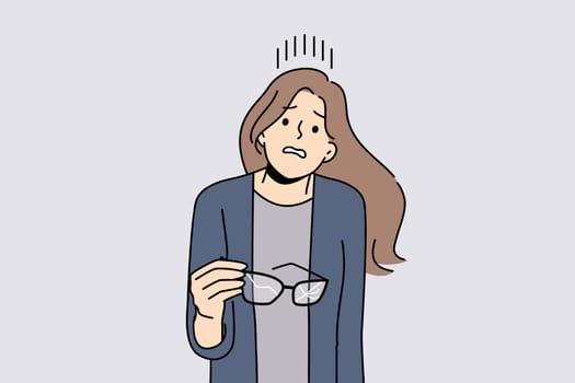 Woman with broken glasses in hands makes confused face not knowing how to solve vision problem