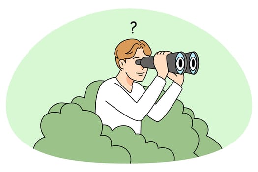 Man looking in binoculars from bush