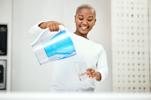 Black woman, pitcher and glass with water filter for clean and fresh purification at home. Happy female person pouring healthy aqua beverage for nutrition, drinking and cold filtration jug in kitchen