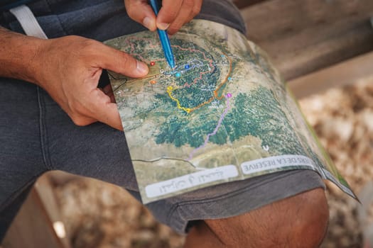 Conceptual photo of an active traveler in the forest. Closeup photo of a man searching the right way to destination on the map.