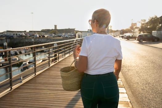 Rear View Of Mature Tourist Lady Walking Along Seaside Promenade