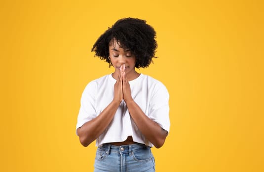 Serious millennial black woman in casual doing pray gesture with hands