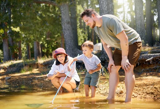 Family, son and fishing net at lake for holiday or fun with happiness or adventure in summer. Vacation, parents and boy with water at forest for travel with mother and father for quality time.