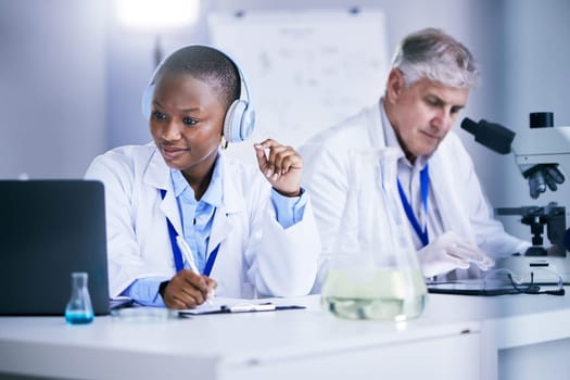Science, laptop and people writing in a laboratory with internet, medical research or results. Man and black woman scientist or doctor with tech and headphones for scientific innovation or planning