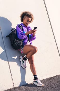 stylish african sportswoman using a mobile phone