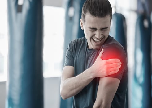 Hand, shoulder pain and the arm of a man in red highlight during a fitness workout. Healthcare, medical and emergency with a male athlete holding his joint after an accident or injury in the gym