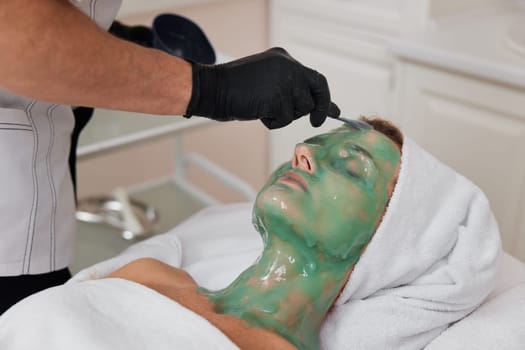 beautician applies alginate mask to the face of woman