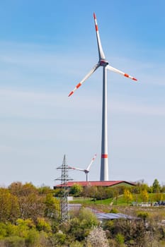 Wind turbines dominate the landscape next to power poles and photovoltaic panels in Germany