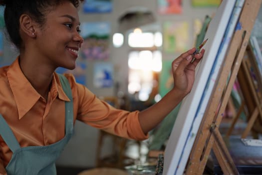 Beautiful american african artist woman painting in art studio at the university classroom