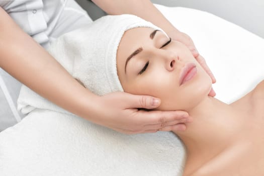 young beautiful woman receiving facial massage at spa salon