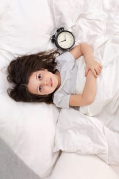 Little girl in pyjamas with clock
