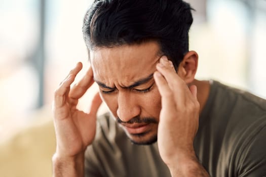 Man, headache and pain in home from stress, mental health fatigue and mind problem. Face, sick and depression of frustrated male person in anxiety, brain fog and dizzy from failure, worry and vertigo
