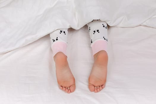 Pair of kid bare feet in bed
