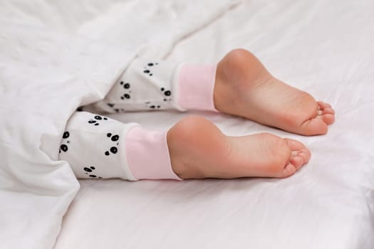 Pair of kid bare feet in bed