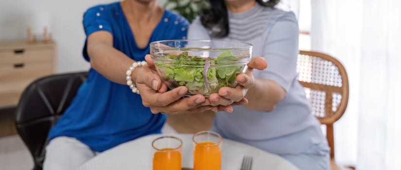 Two old women eat salad healthy food at living room