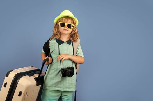 Child traveler with suitcase isolated on studio background. Tourist kid boy. Portrait of child travel with travel bag. Travel, adventure, vacation.