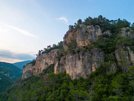 Steep rocky cliffs over forested landscape at golden hour
