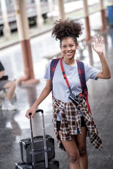 Young female traveler walking standing with a suitcase at train station. woman traveler tourist walking standing smiling