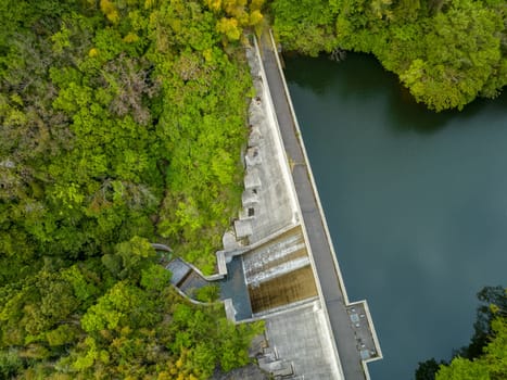 Aerial view of concrete dam and reservoir in green forest