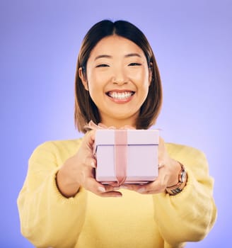 Portrait, smile and Asian woman with a gift, box and celebration against a studio background. Face, happy female person or model with happiness, present and giveaway with a ribbon, surprise and prize.