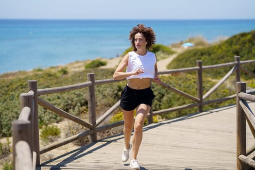 Active woman in sportswear jogging near ocean