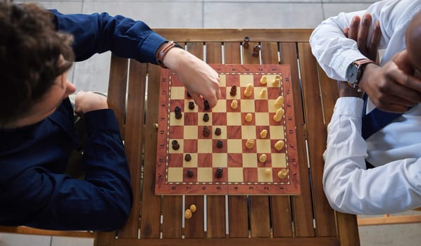 Chess, board game and business men playing at a table from above while moving piece for strategy. Male friends together to play, relax and bond with icon for problem solving, challenge or checkmate