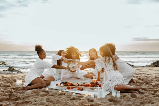 Group of young women toasting with champagne, having bachelorette party celebration on the beach