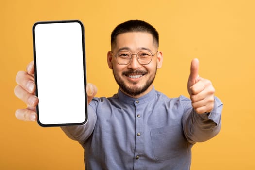 I Recommend. Cheerful Young Asian Male Showing Blank Smartphone And Thumb Up