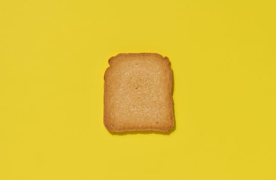 One slice of white wheat toast on a yellow background, top view