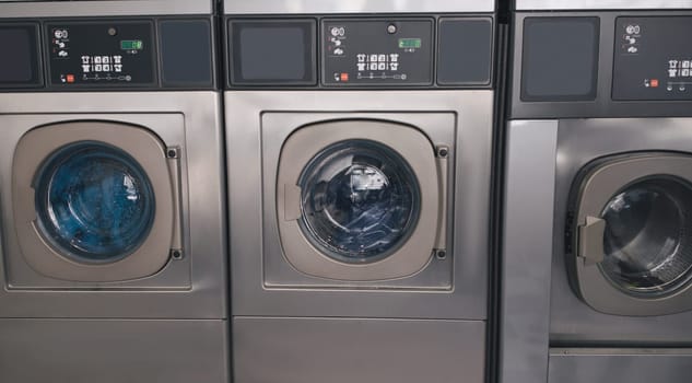 Three Industrial Washing Machines In Laundromat In A Row Indoors
