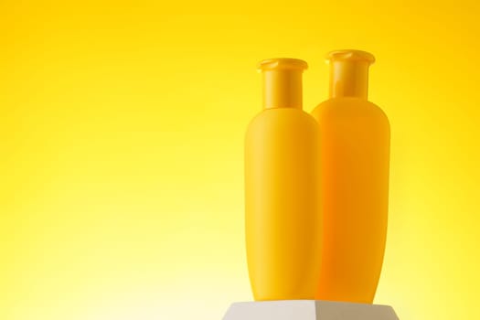Cosmetic bottle with sunscreen lotion on yellow background