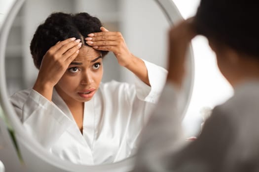 Worried Young Black Woman Checking Her Hair Roots At Home