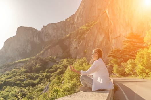 Yoga woman mountains. Profile of a woman doing yoga in the top of a cliff in the mountain. Woman meditates in yoga asana Padmasana