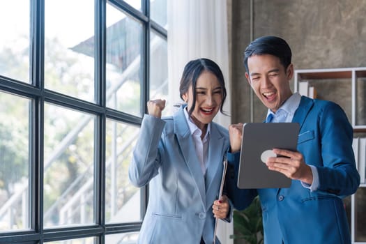 Two asian businesspleplo celebrate with laptop, success happy pose, E-commerce, get good news on laptop. internet technology, or startup small business concept