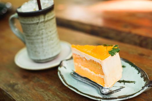 orange cake with ice coffee on wood table