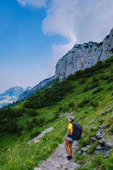 A woman with a backpack stands on top of a mountain, The girl travels to beautiful places, Reaching the goal, mountain ridge at Saxer Lucke, Kreuzberg in Alpstein Appenzell Innerrhoden Switzerland. 