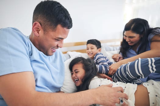 Family, tickle and play on bed with fun and smile in a home with bonding and parent care. Happy, house and bedroom with a father, mom and children together in the morning with dad, mother and kid
