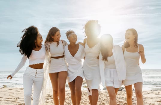 Group of female friends embracing and laughing, walking at the beach, enjoying hen party celebration. Best friends having fun and enjoying their holiday