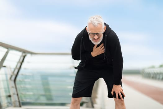 Elderly sportsman with heart pain touching his chest