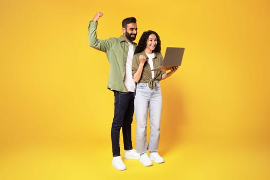 Arabic Couple Holding Laptop Gesturing Yes On Yellow Studio Background