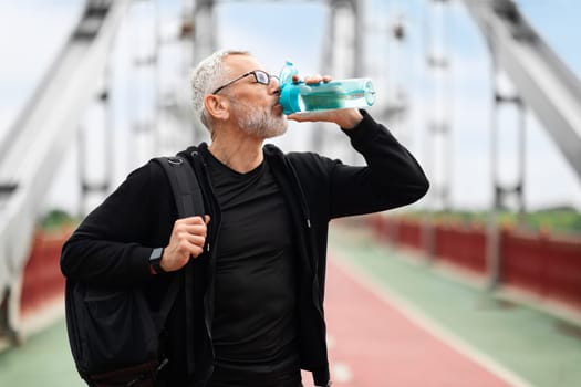 Retired sportsman drinking water after outdoor workout